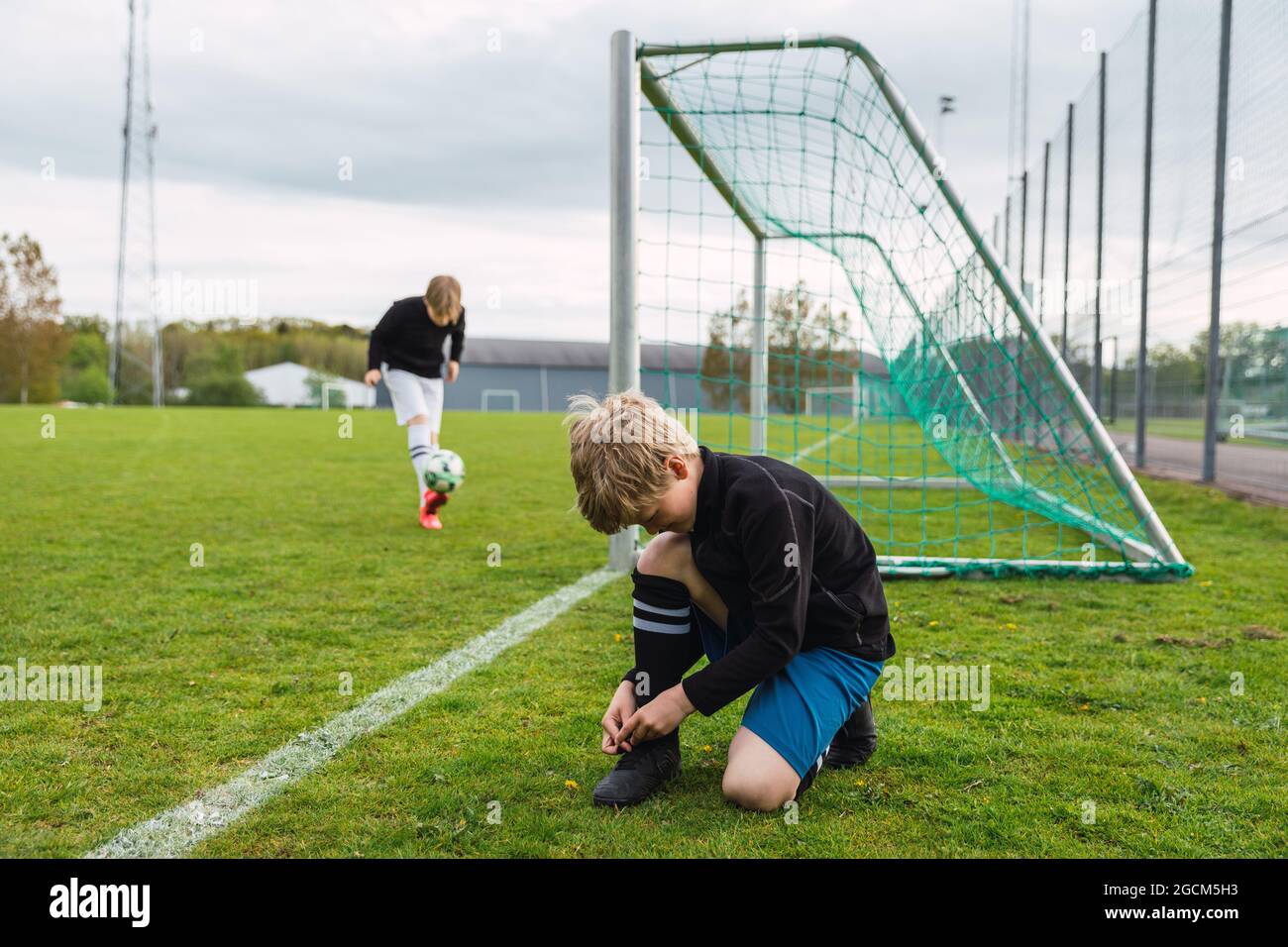 Vista lateral de los cordones de los chicos adolescentes en las botas de  fútbol mientras te preparas para entrenar en el campo Fotografía de stock -  Alamy