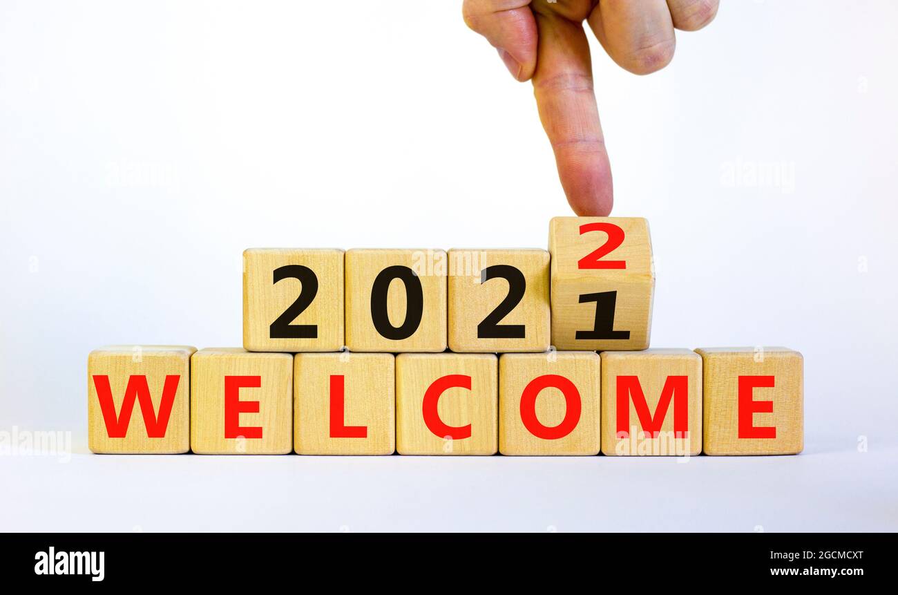 Símbolo de la planificación 2022 BIENVENIDO AÑO NUEVO. Businessman  convierte un cubo de madera y cambia las palabras &#39;Welcome 2021&#39; a &#39;Welcome  2022&#39;. Hermoso backgrou blanco Fotografía de stock - Alamy