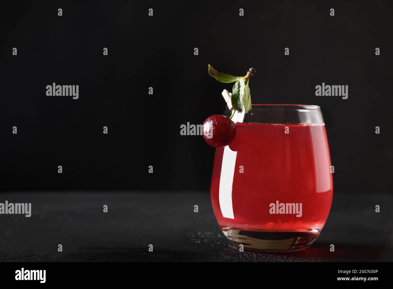 Copa de bebida fresca de cereza roja o compota de verano casera sobre fondo negro. Primer plano. Foto de stock