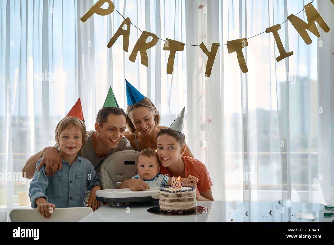 Feliz familia joven con amigos celebra el cumpleaños de un niño de 8 meses.  El primer año de vida. Fiesta en casa Fotografía de stock - Alamy