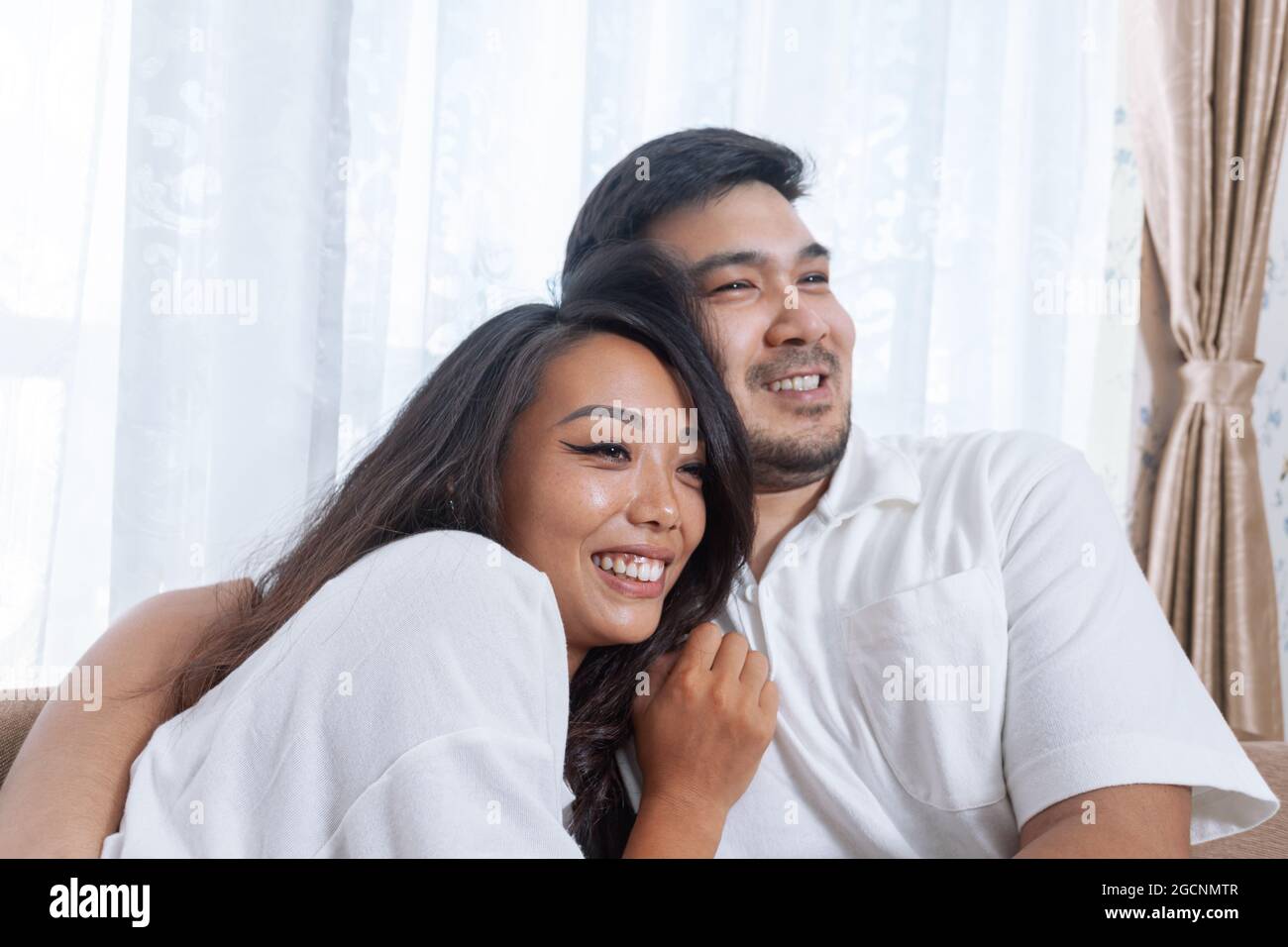 Joven feliz pareja asiática relajándose juntos en casa Foto de stock