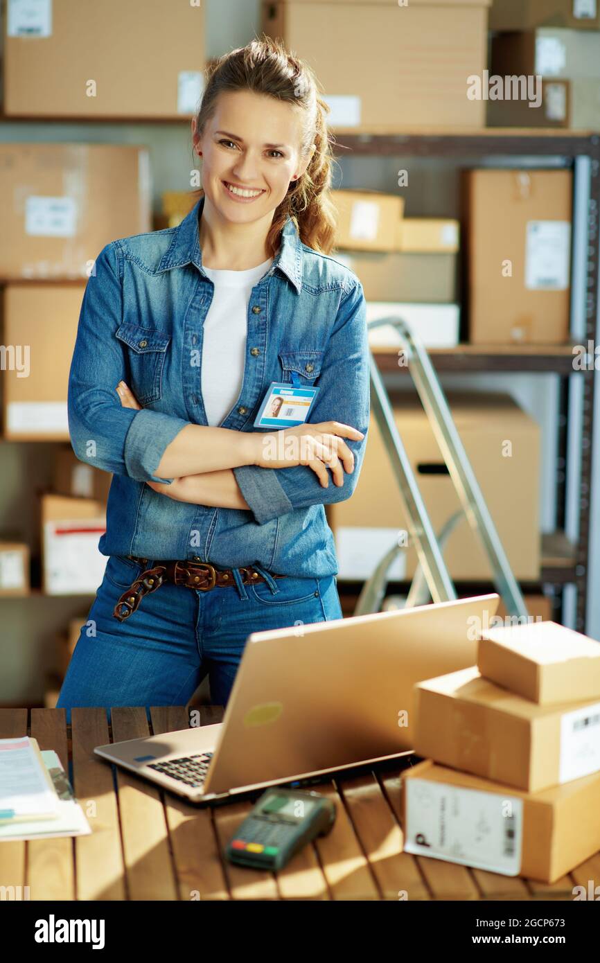Negocio de entrega. Mujer moderna sonriente en jeans con ordenador portátil  y paquetes en la oficina Fotografía de stock - Alamy