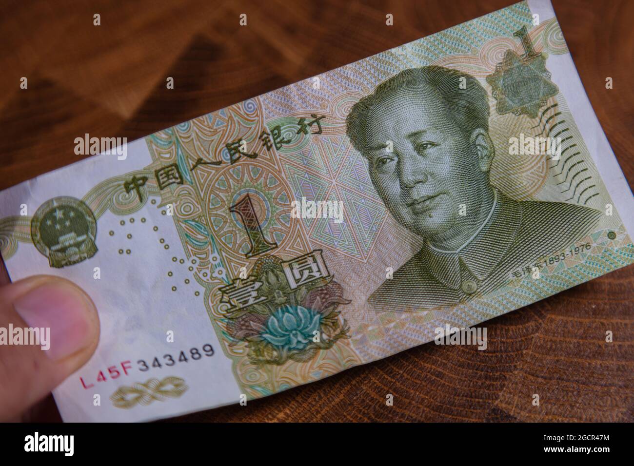 La mano masculina sostiene fan de 1 renminbi o yuan chino o billete abreviado de RMB, la moneda oficial de la república Popular de china. En la parte delantera Foto de stock