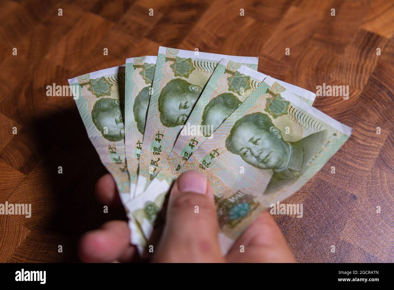 La mano masculina sostiene fan de 1 renminbi o yuan chino o billete abreviado de RMB, la moneda oficial de la república Popular de china. En la parte delantera Foto de stock