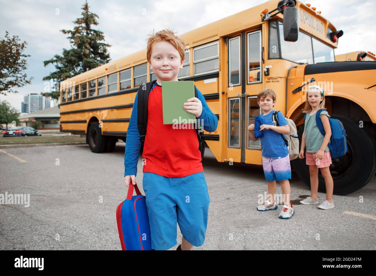 Felices niños caucásicos niños y niñas estudiantes de pie en el autobús escolar amarillo. Educación y vuelta a la escuela en septiembre. Amigos compañeros de escuela Cla Foto de stock