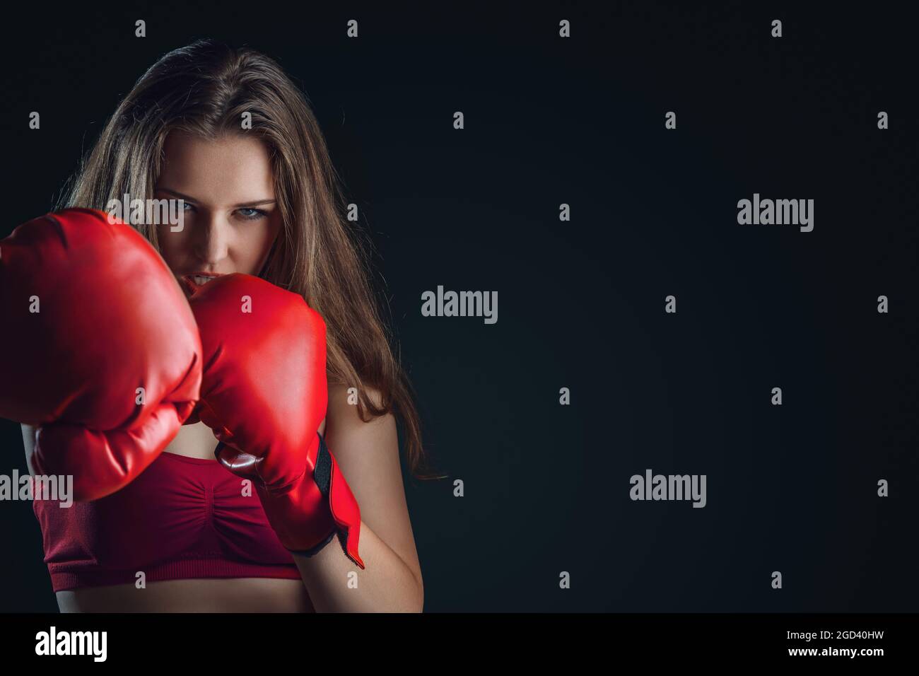 Mujer joven con guantes de boxeo aislados sobre fondo oscuro Foto de stock