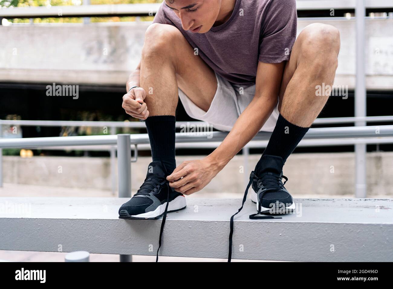 Hombre joven de ata sus cordones zapatillas antes de hacer trucos de parkour en la ciudad Fotografía stock - Alamy