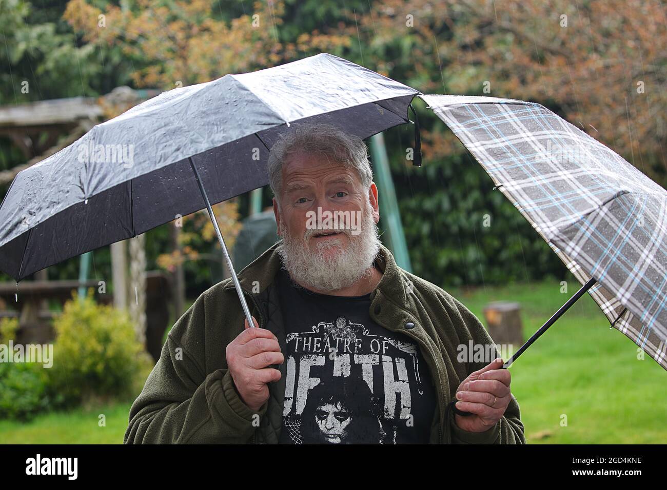 Hombre parado bajo la lluvia con dos sombrillas .jpg Fotografía de stock -  Alamy