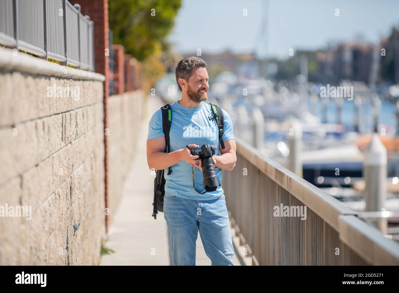 El hombre sostiene la cámara de pie en el paseo marítimo. Fotografía de vacaciones. Fotografía de viajes Foto de stock