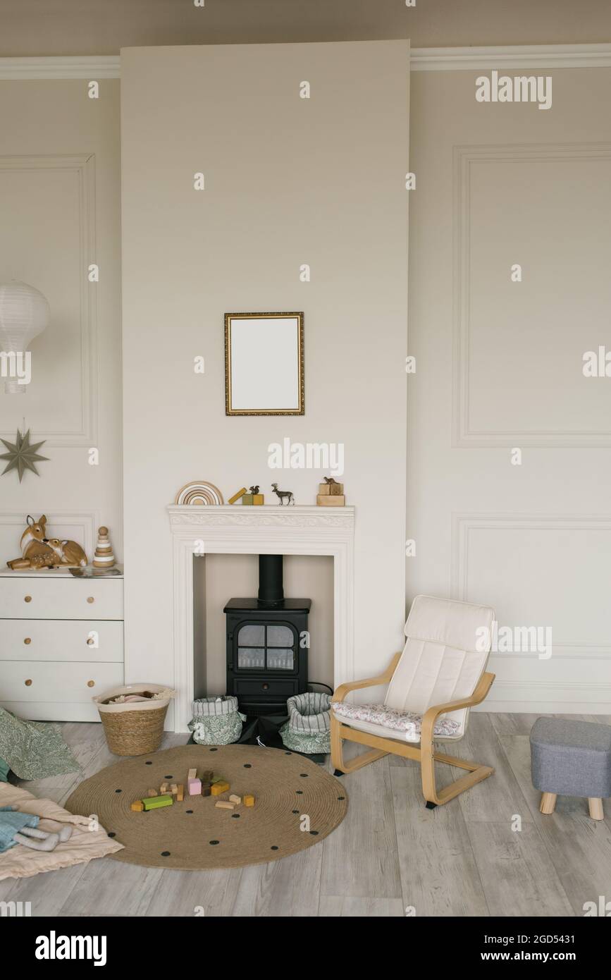 Habitación infantil de estilo escandinavo. Chimenea negra retro en un nicho en la pared, un asiento para niños y una cómoda blanca Foto de stock