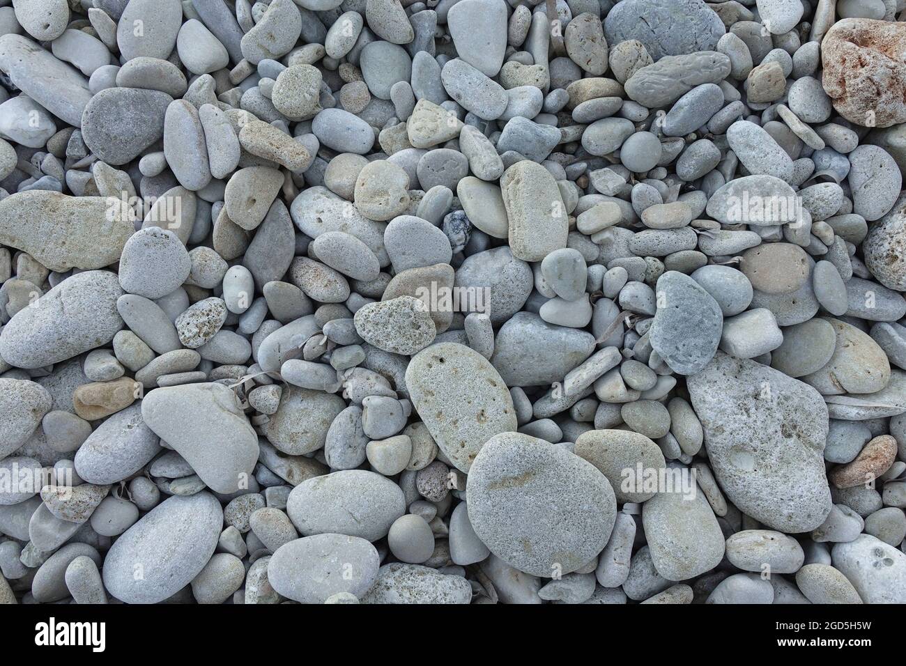 Guijarros en una playa rocosa. Piedras y pequeñas rocas de fondo. Foto de stock