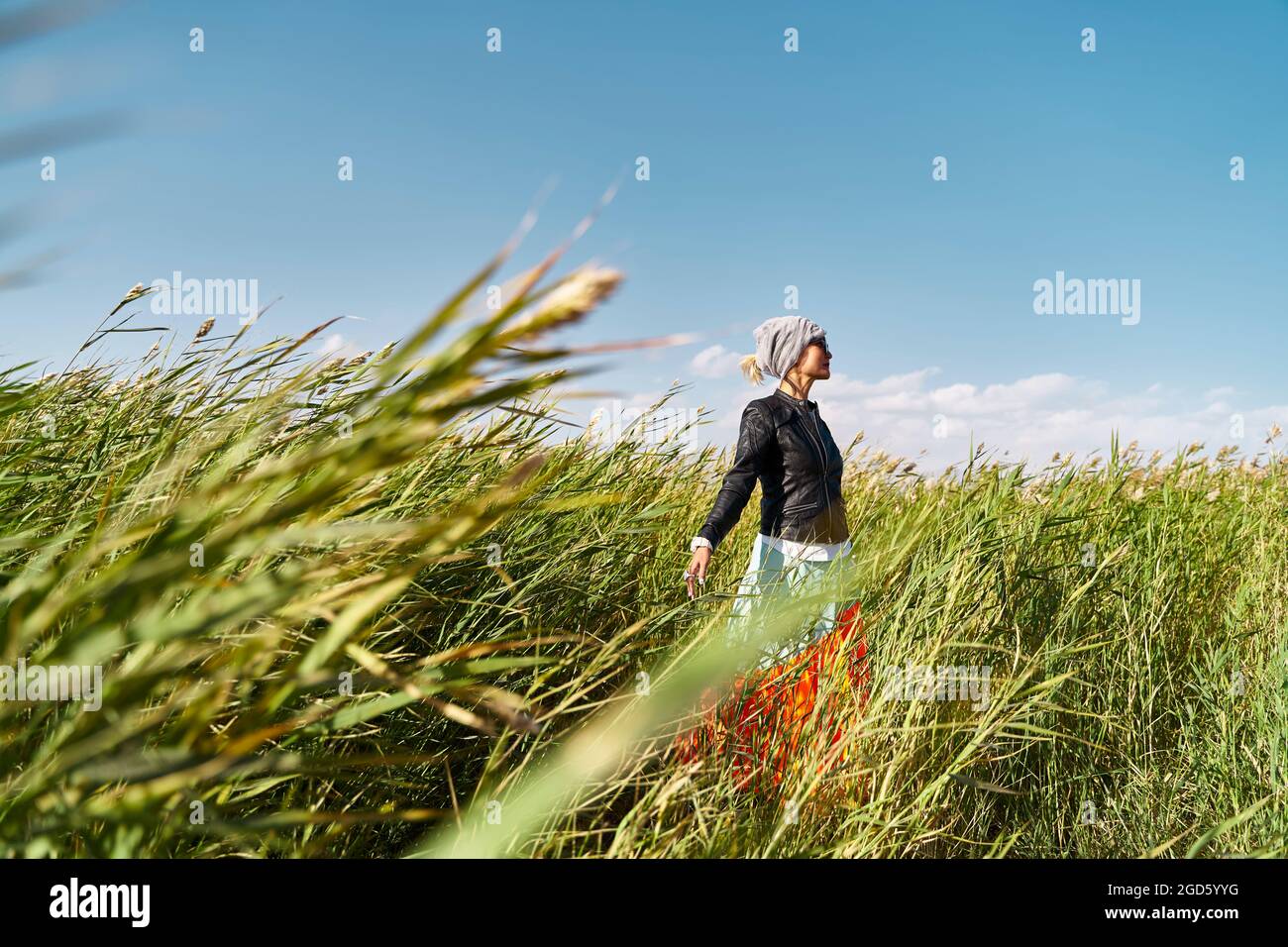 mujer asiática disfrutando del aire fresco y la luz del sol en un campo de cañas Foto de stock