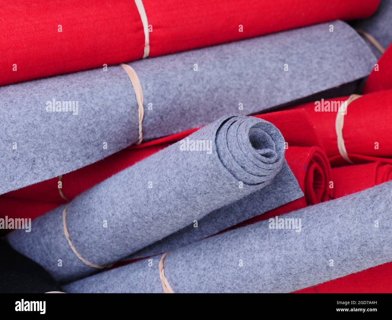 alfombrillas rojas y grises atadas con una cuerda, almacenadas mezcladas. Foto de stock