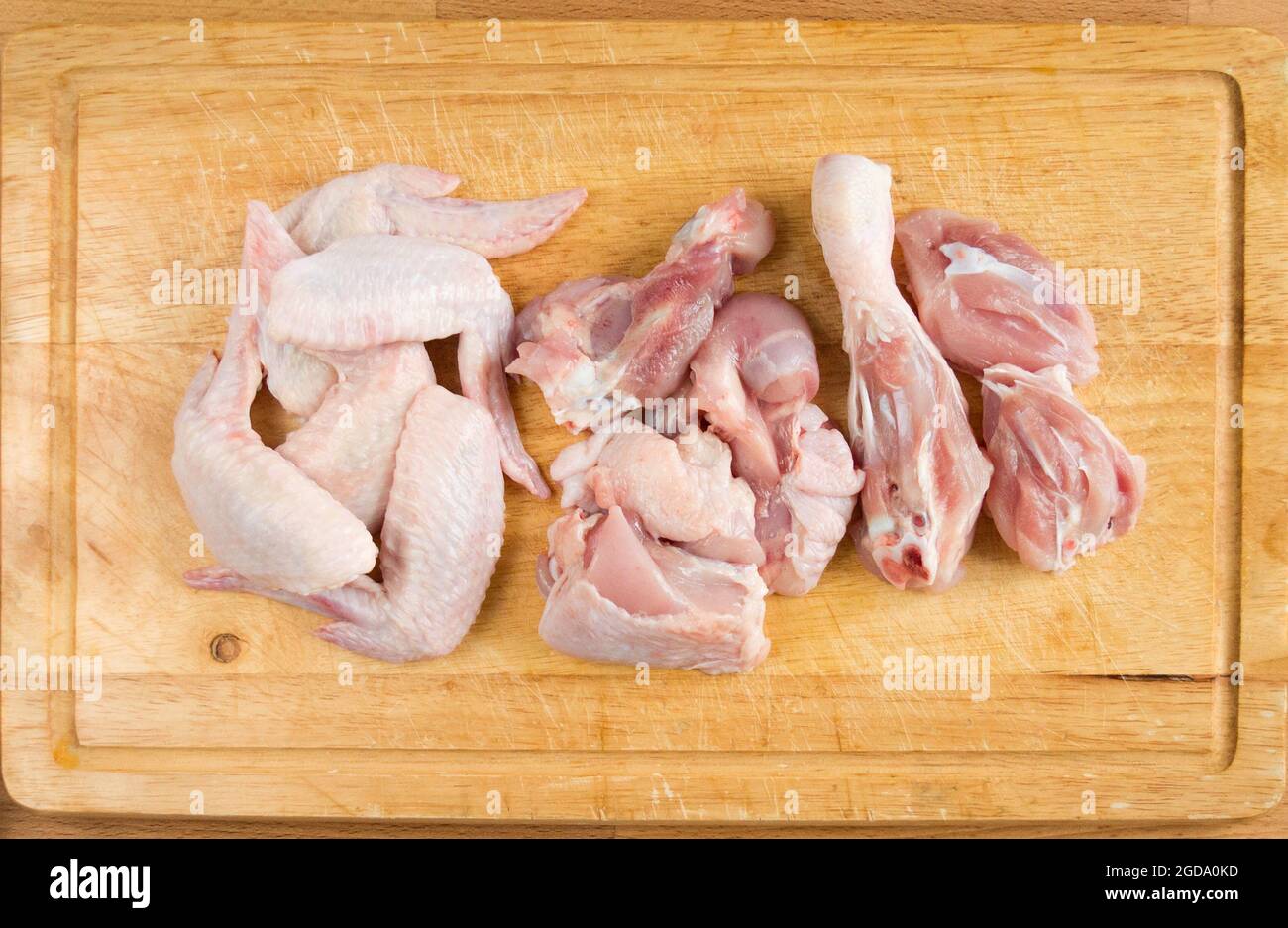 Pollo cortado en trozos en una tabla de cortar. Foto de stock