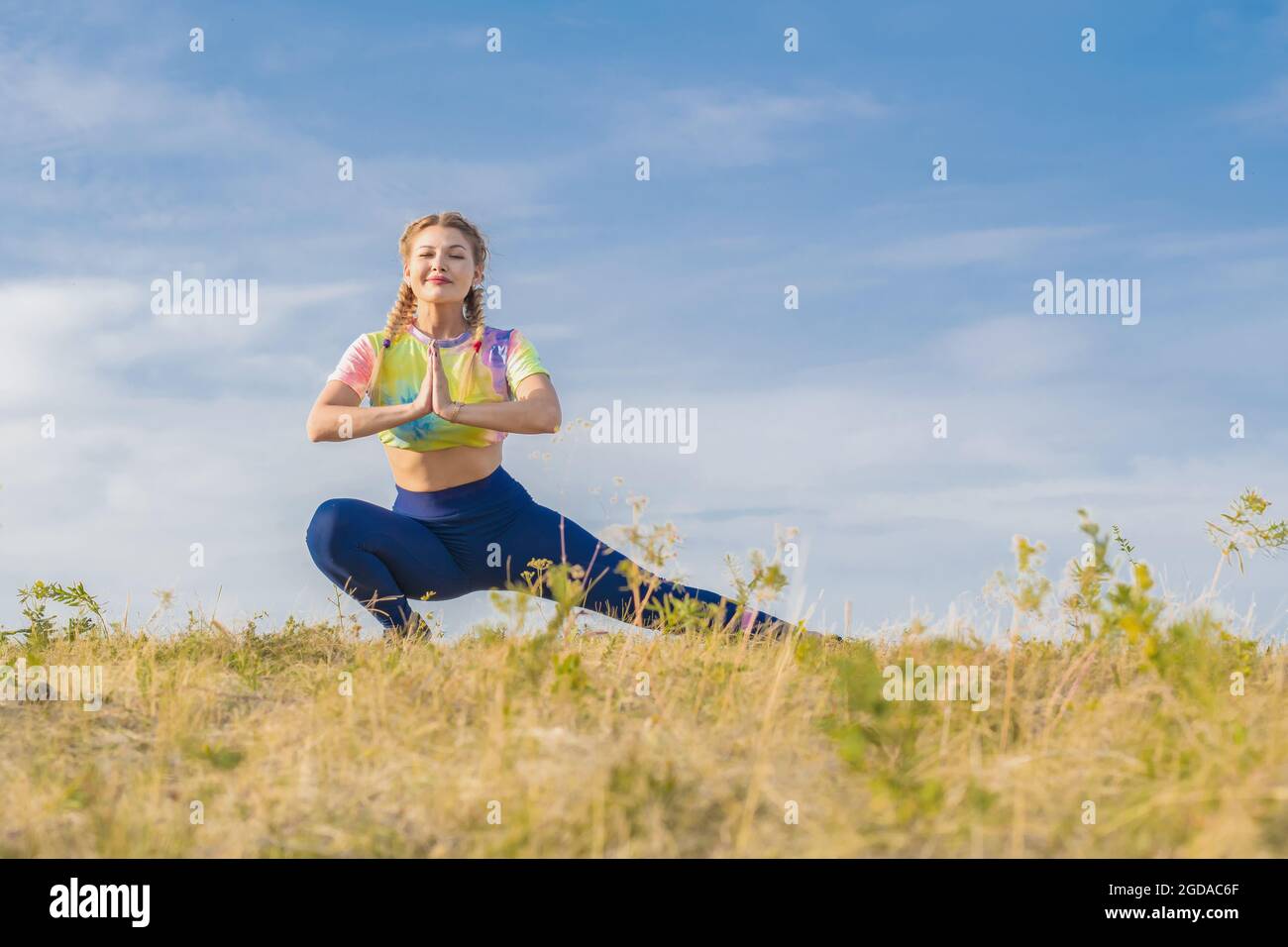 Chica joven en chándal brillante se dedica a yoga y gimnasia contra el  fondo del cielo azul Fotografía de stock - Alamy