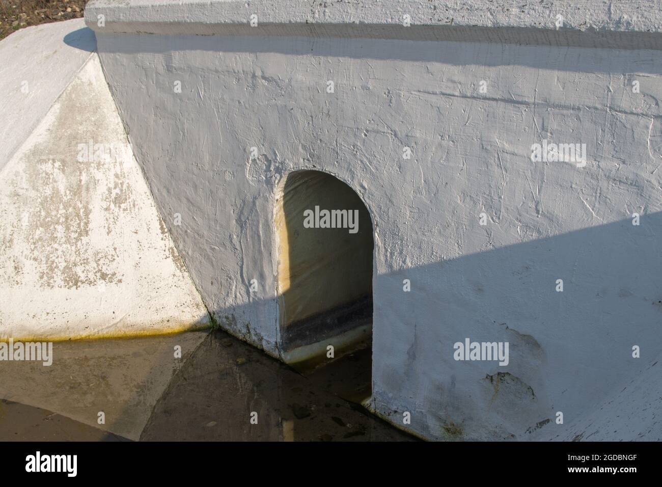 Pintado de hormigón blanco diseño de zanja de drenaje con agujero en la forma de un arco con la losa del piso debajo de la carretera o la superficie del carril con agua de lluvia en el bo Foto de stock