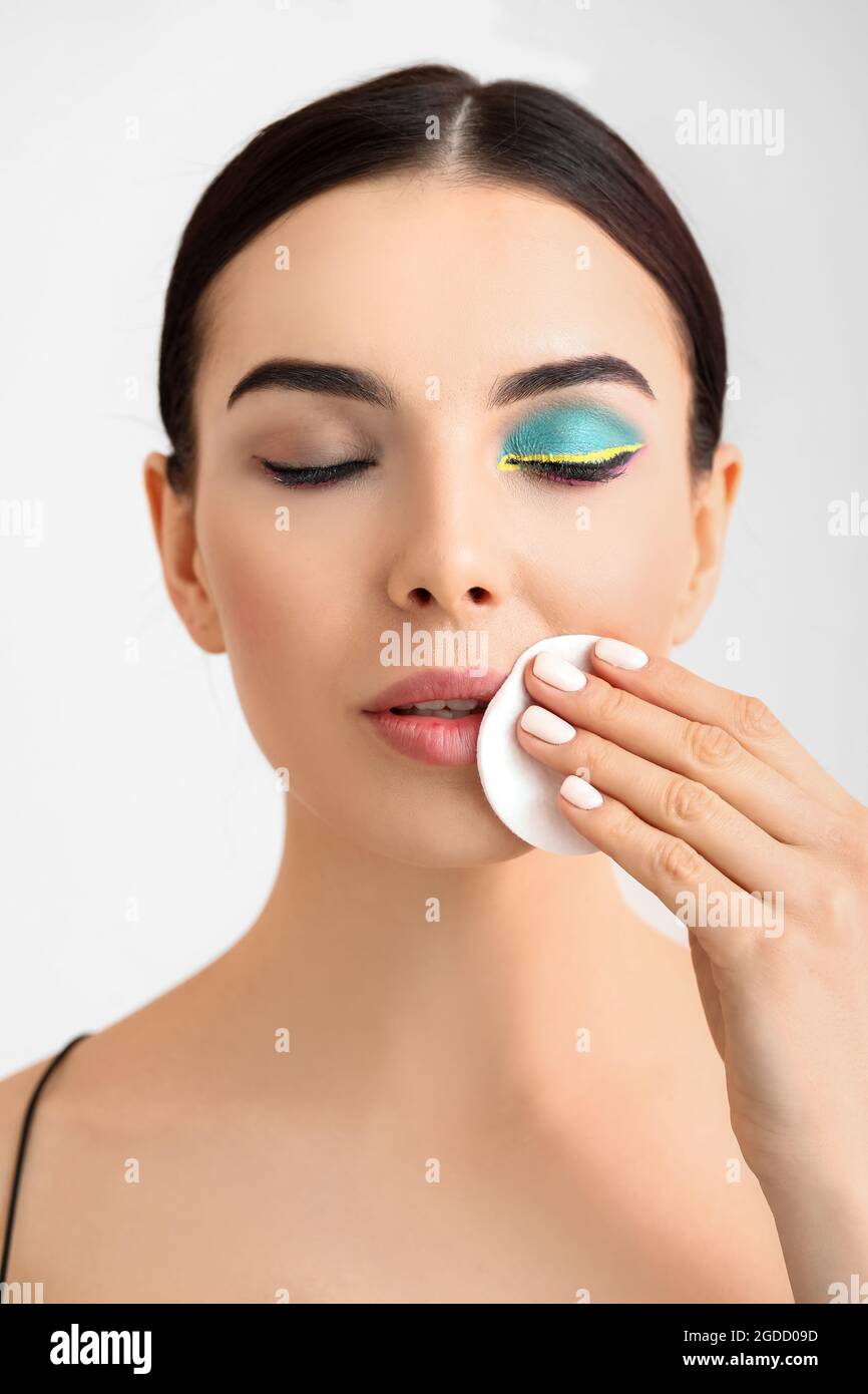 Hermosa mujer joven quitar maquillaje sobre fondo claro Fotografía de stock  - Alamy