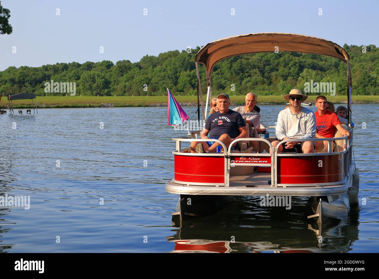 Gente disfrutando de una excursión en barco pontón en un lago en un soleado y cálido día de verano Foto de stock