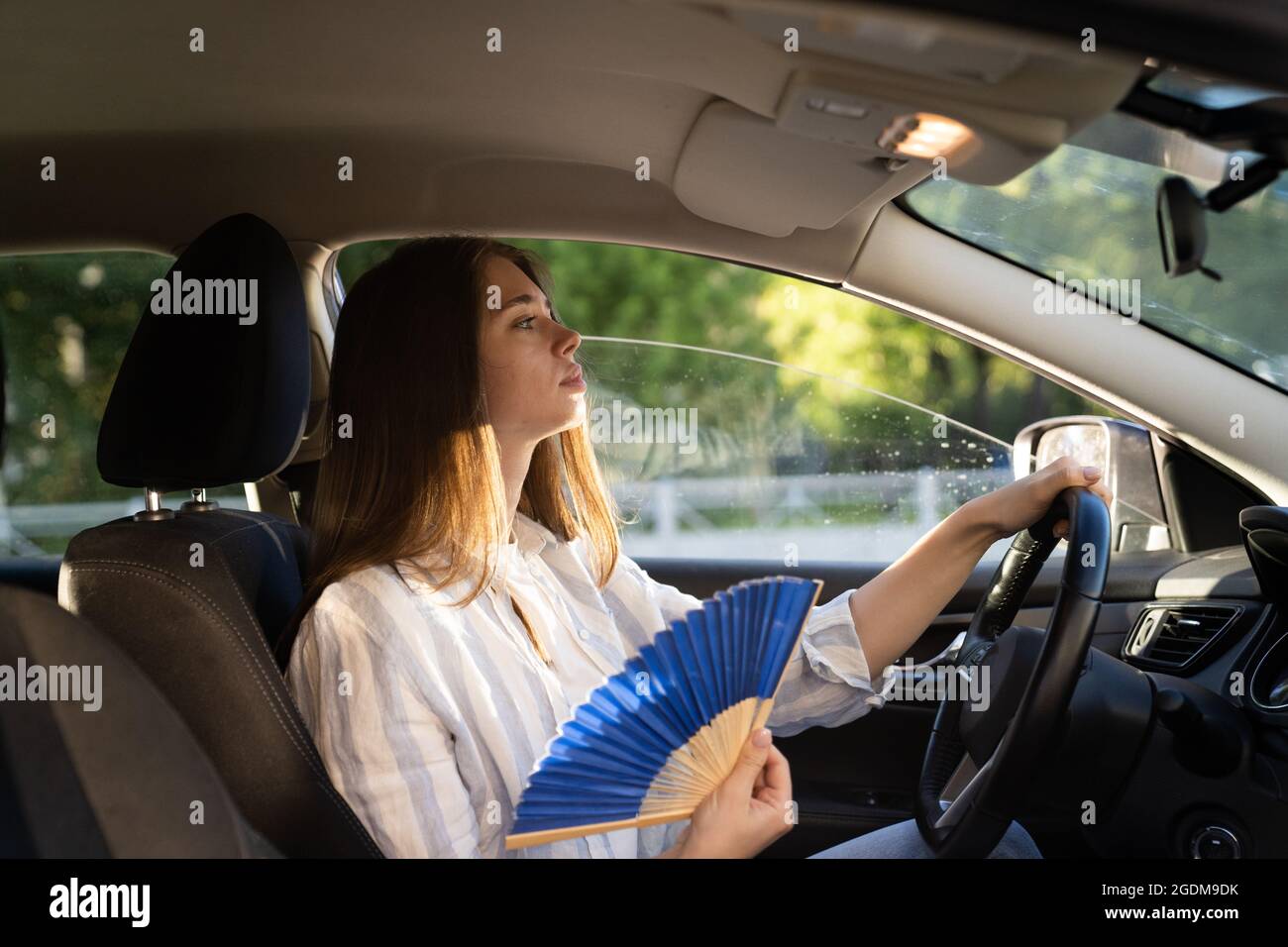 Chica conductor con ventilador de mano que sufre de calor en el coche,  tiene problemas con el aire acondicionado que no funciona Fotografía de  stock - Alamy