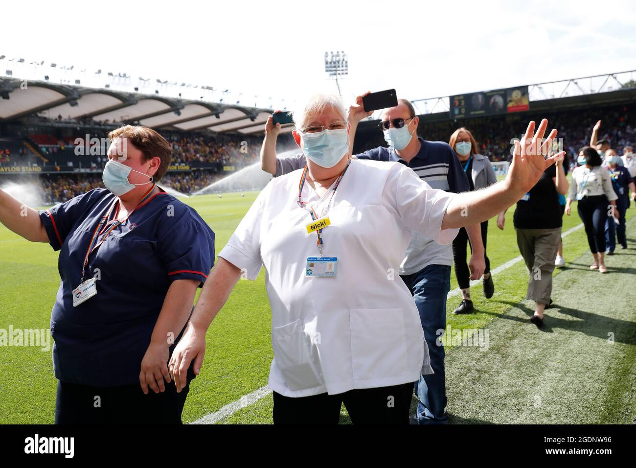 14th de agosto de 2021; Vicarage Road Stadium, Watford, Herts, Inglaterra; Fútbol de la Premier League, Watford versus Aston Villa; personal y voluntarios del Hospital General Watford caminan por un guardia de honor a media hora mientras son aplaudidos por los fans de Watford y Aston Villa por luchar con el Coronavirus Foto de stock