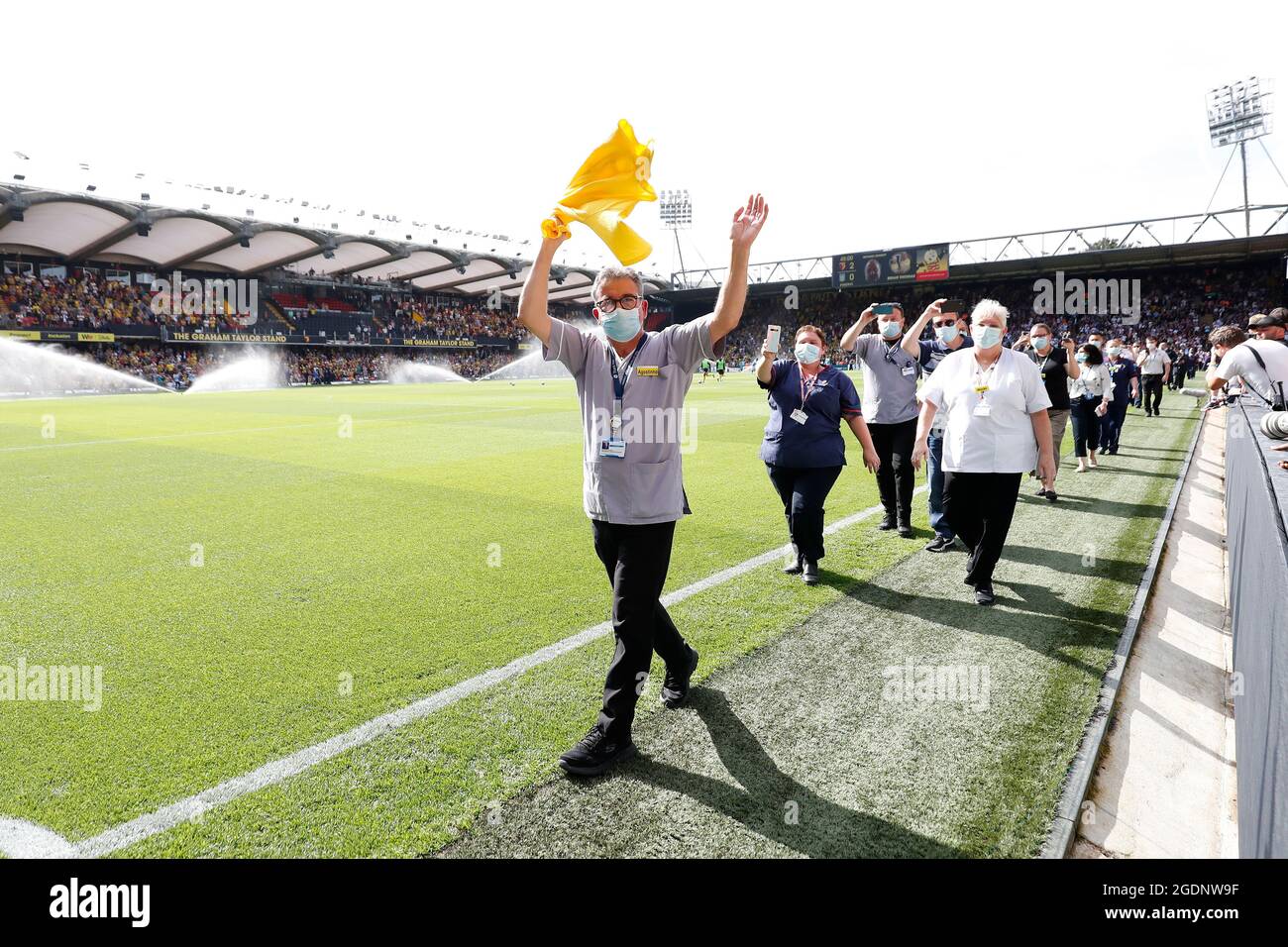 14th de agosto de 2021; Vicarage Road Stadium, Watford, Herts, Inglaterra; Fútbol de la Premier League, Watford versus Aston Villa; personal y voluntarios del Hospital General Watford caminan por un guardia de honor a media hora mientras son aplaudidos por los fans de Watford y Aston Villa por luchar con el Coronavirus Foto de stock