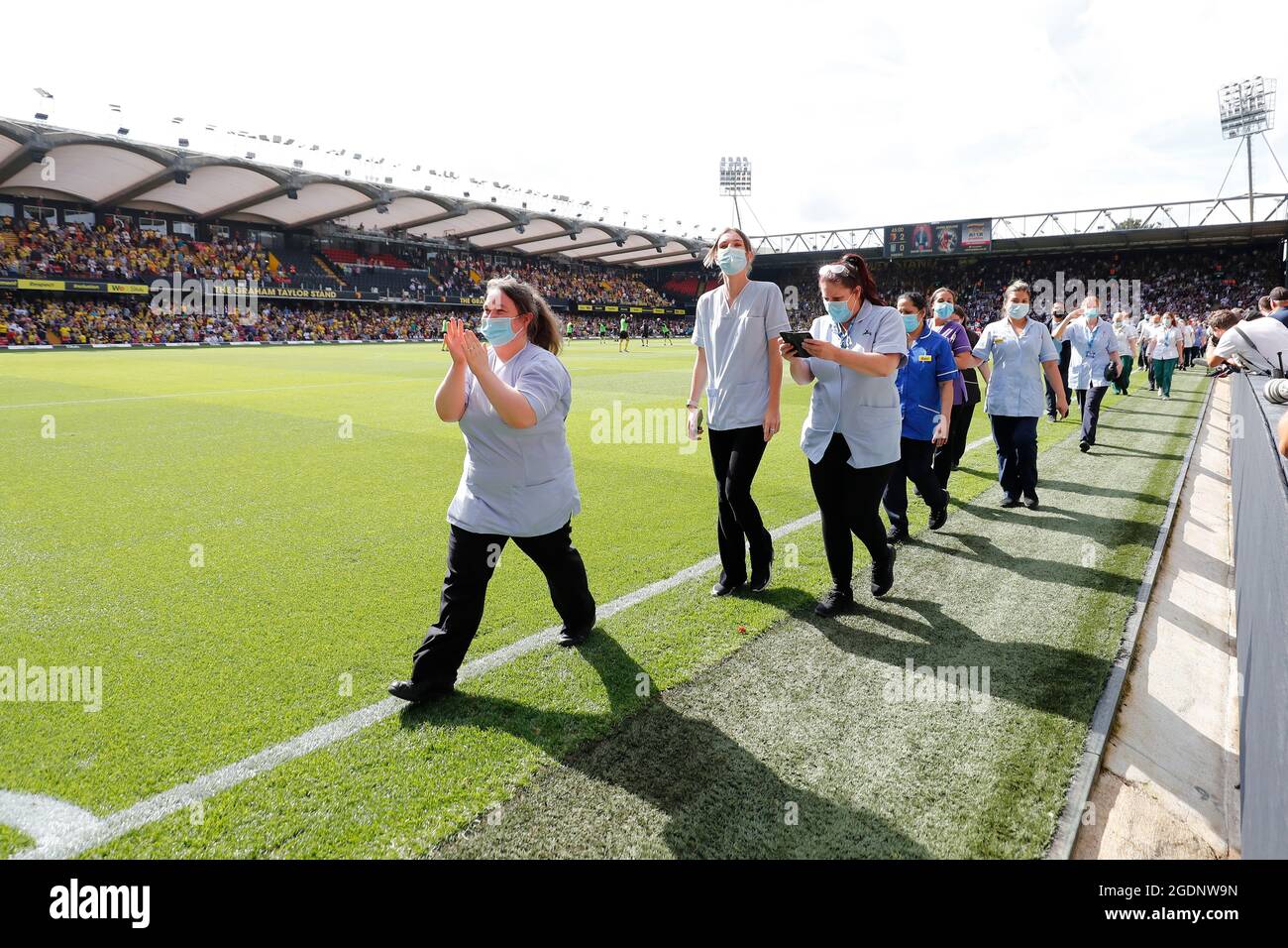 14th de agosto de 2021; Vicarage Road Stadium, Watford, Herts, Inglaterra; Fútbol de la Premier League, Watford versus Aston Villa; personal y voluntarios del Hospital General Watford caminan por un guardia de honor a media hora mientras son aplaudidos por los fans de Watford y Aston Villa por luchar con el Coronavirus Foto de stock