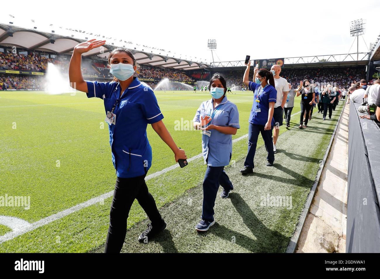 14th de agosto de 2021; Vicarage Road Stadium, Watford, Herts, Inglaterra; Fútbol de la Premier League, Watford versus Aston Villa; personal y voluntarios del Hospital General Watford caminan por un guardia de honor a media hora mientras son aplaudidos por los fans de Watford y Aston Villa por luchar con el Coronavirus Foto de stock