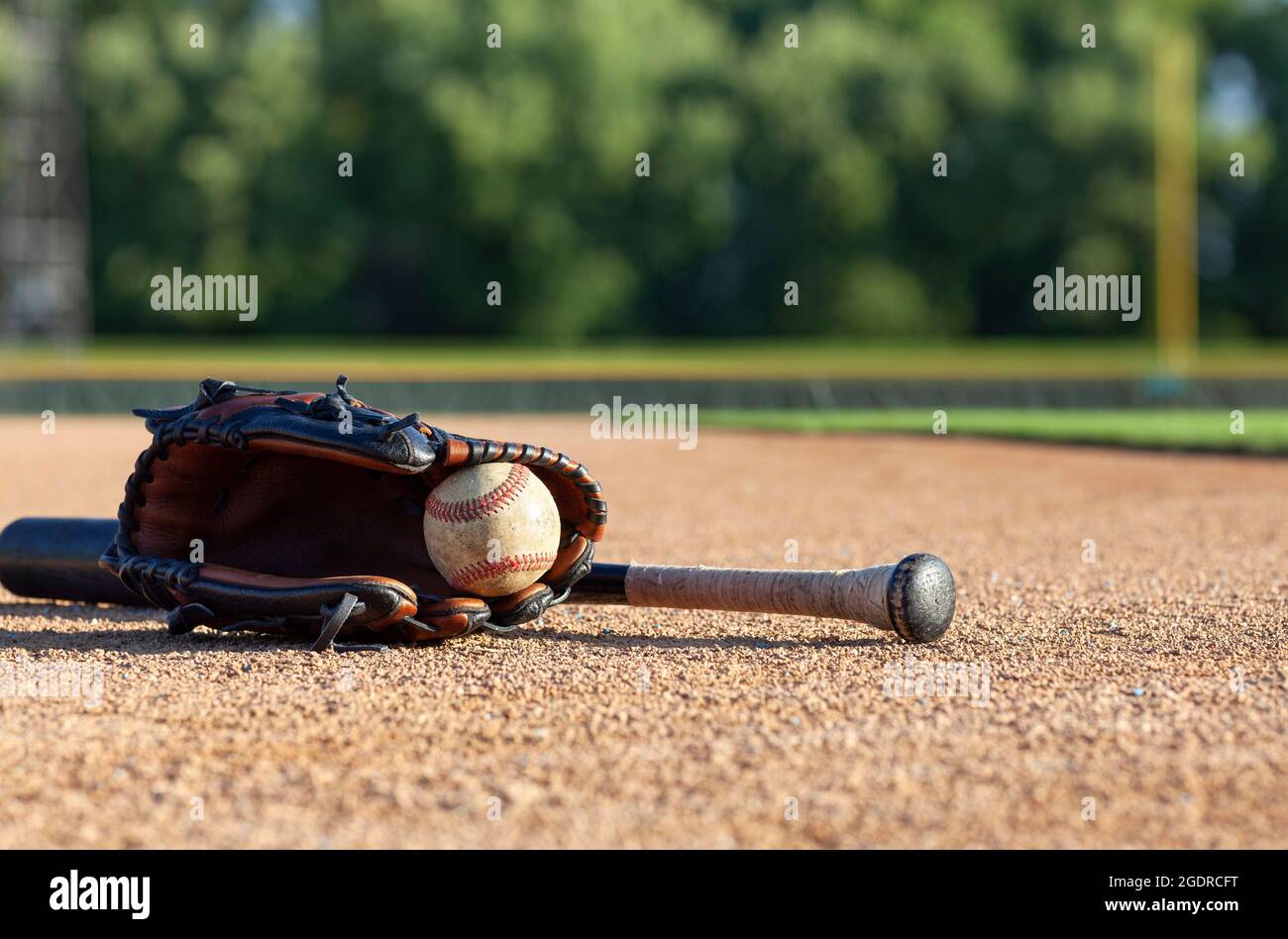 Béisbol en una mitón con un bate negro de ángulo bajo selectivo de enfoque en un campo de béisbol Foto de stock