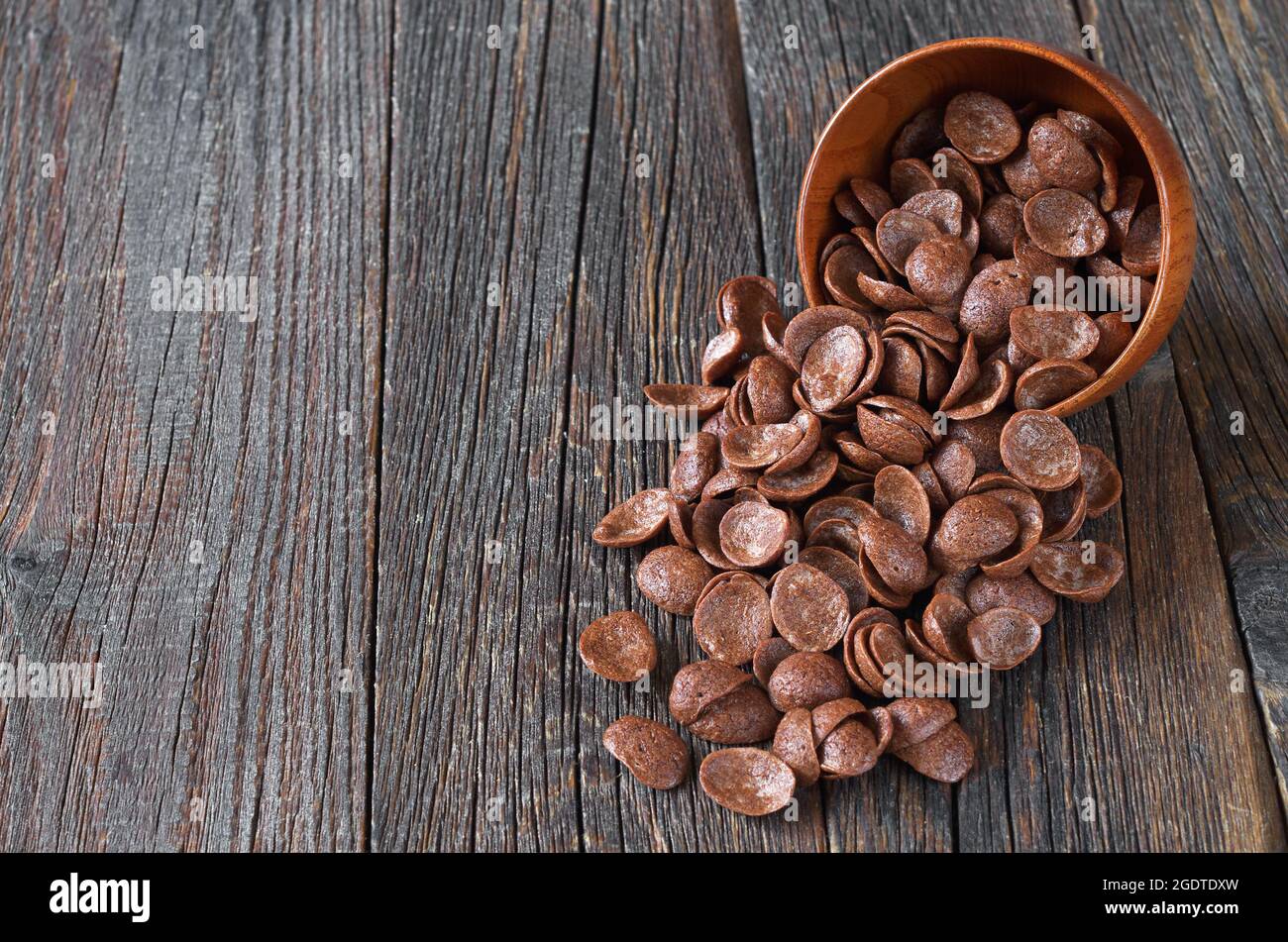 Cereales de chocolate en un tazón marrón sobre un viejo fondo de madera con espacio para texto Foto de stock