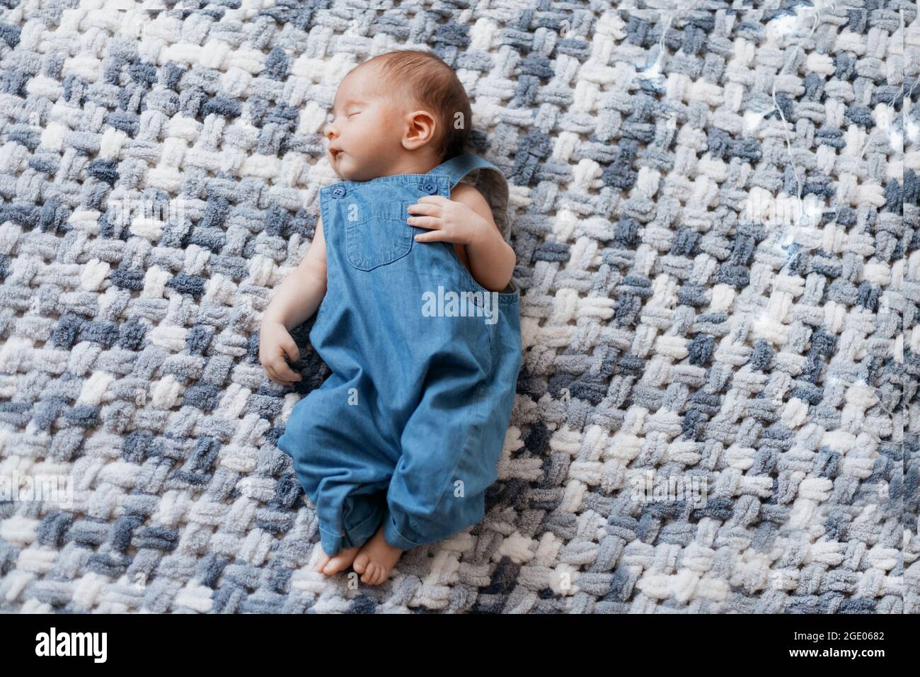 bebé recién nacido en un mono azul tumbado sobre manta de punto Fotografía de stock - Alamy
