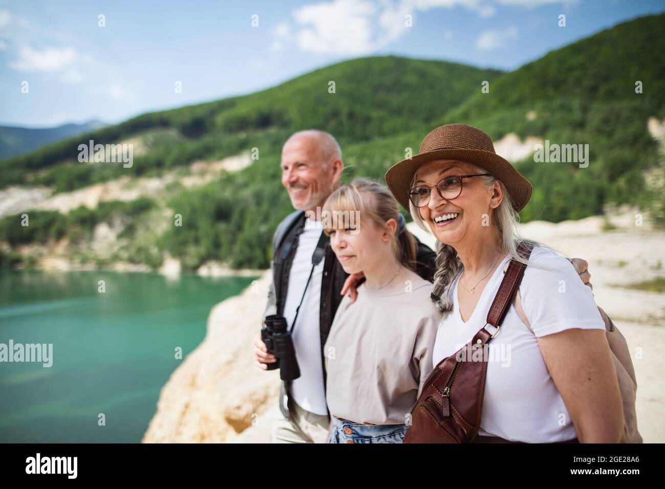 Feliz preadolescente con abuelos en viaje de senderismo en vacaciones de verano, caminando. Foto de stock