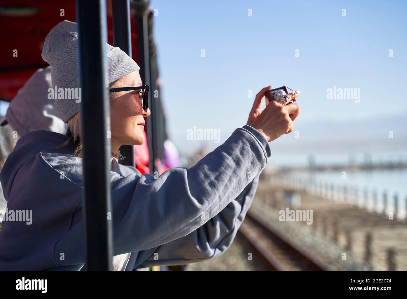 mujer asiática turística tomando una foto usando un teléfono móvil en un tren turístico Foto de stock
