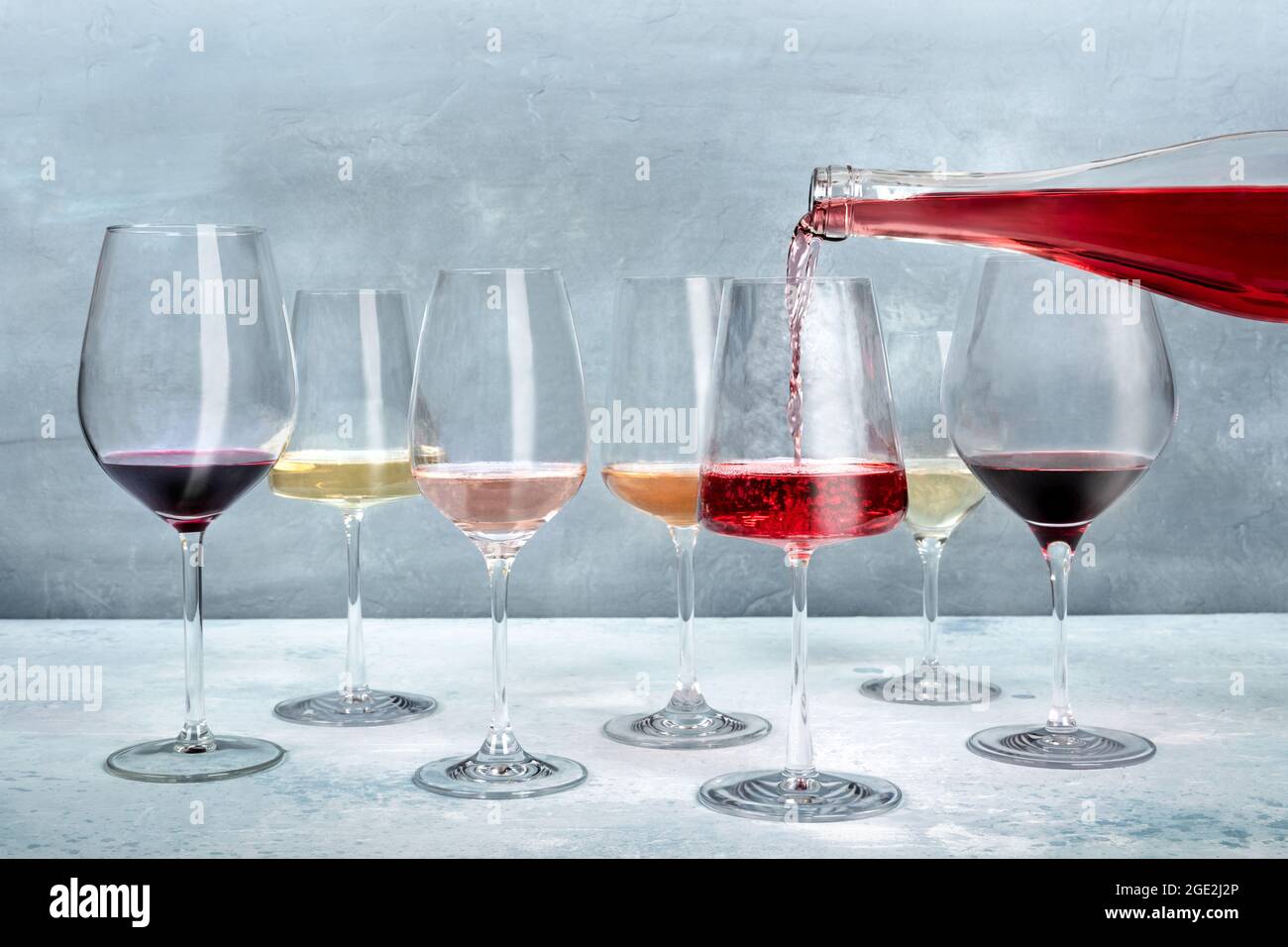 Vino rosado servido en una copa en una degustación, con vino blanco y tinto de varios colores. Evento de cata de vinos Foto de stock