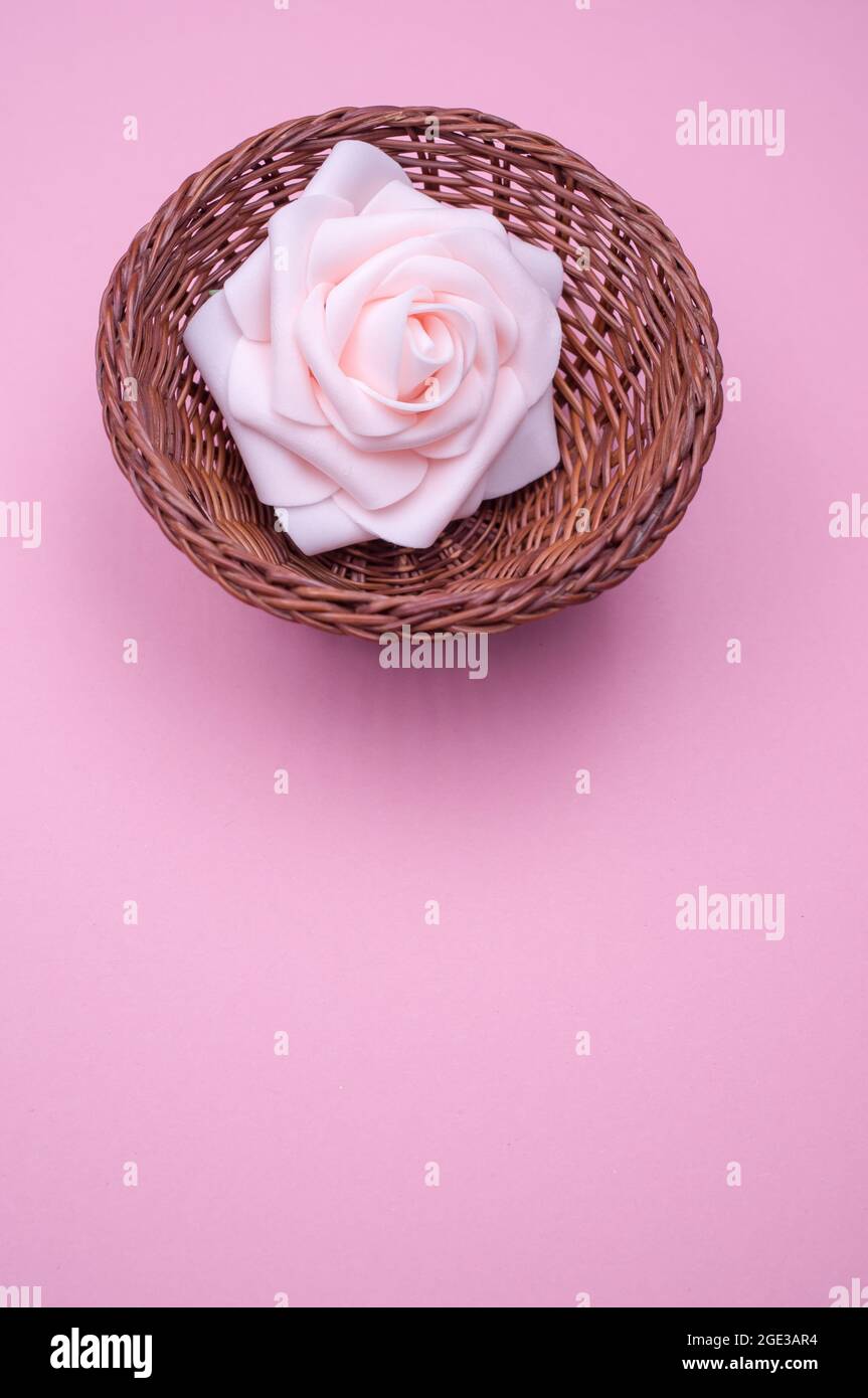 primer plano vertical de una rosa artificial en una pequeña cesta sobre  fondo rosa estético Fotografía de stock - Alamy