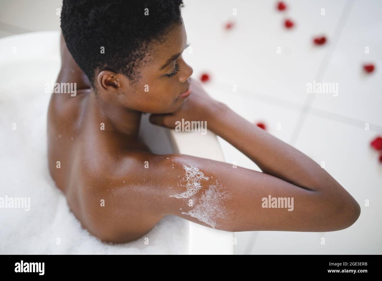 Sonriente mujer afroamericana en el baño relajándose en la bañera de espuma Foto de stock