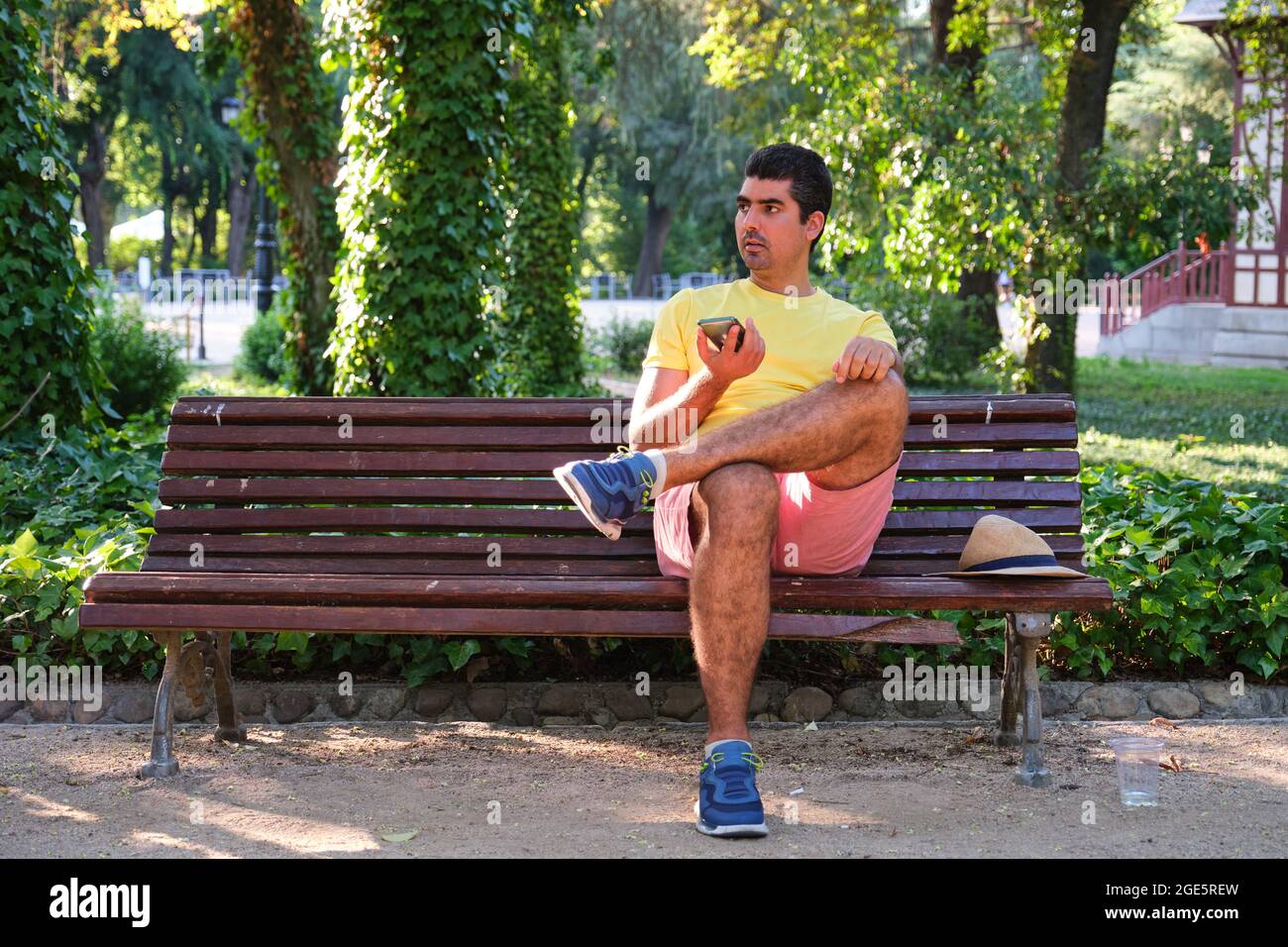 Hombre sentado en un banco grabando una nota de audio con las piernas