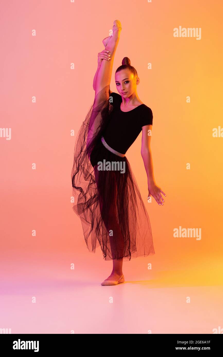 Una niña, artista de gimnasia rítmica en traje de escenario, falda aislada sobre fondo de estudio amarillo rosa en Concepto de deporte Fotografía de stock - Alamy