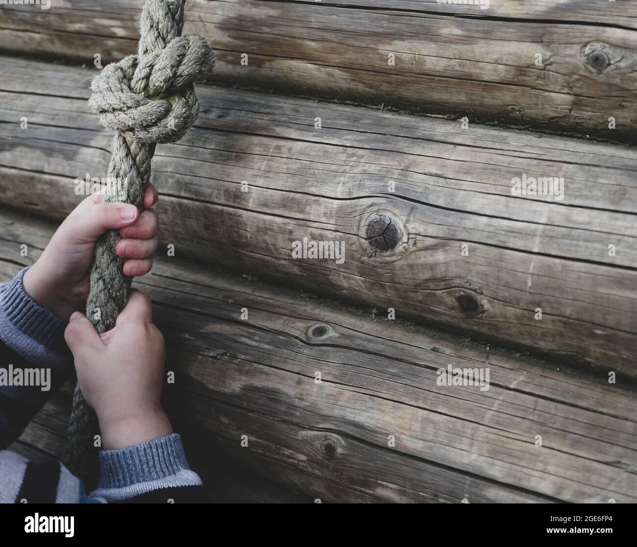 niño pequeño tirando de sí mismo sobre la cuerda - niño pequeño jugando en el patio de juegos con una cuerda Foto de stock