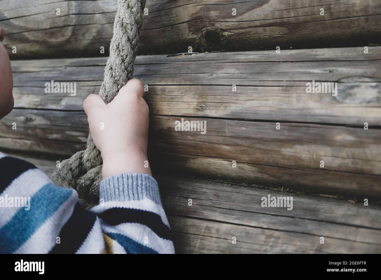 niño pequeño tirando de sí mismo sobre la cuerda - niño pequeño jugando en el patio de juegos con una cuerda Foto de stock