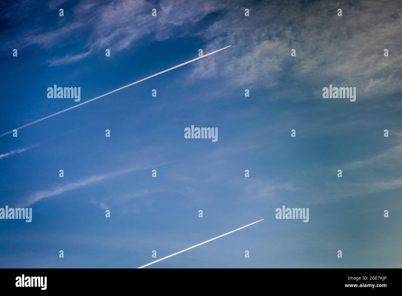 Dos aviones vuelan alto creando senderos blancos contra el cielo azul, Inglaterra. Foto de stock