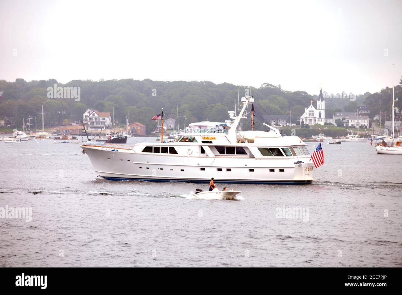 Un pequeño barco pasa por un yate de lujo anclado en Boothbay Haror, Maine, Estados Unidos Foto de stock