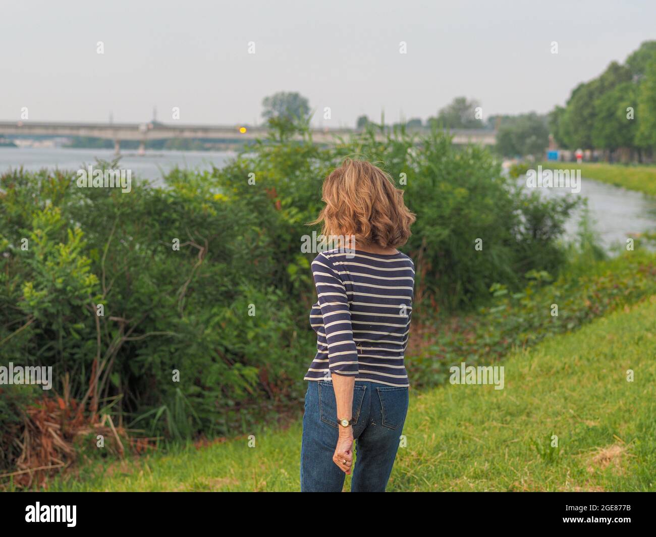 Mujer mayor caucásica con una camisa a rayas y pantalones vaqueros en un  parque Fotografía de stock - Alamy