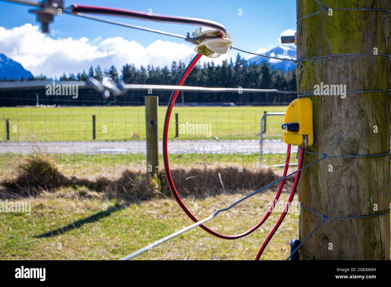 Cercado de alambre y poste de la granja con alambre eléctrico superior en una granja en el país alto, Canterbury, Nueva Zelanda Foto de stock