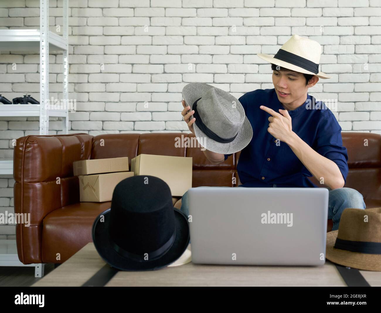 Joven asiático hombre vender varios estilos brim sombrero en línea a través de la aplicación en el ordenador portátil. Concepto negocio para el hogar pequeño Fotografía de stock - Alamy