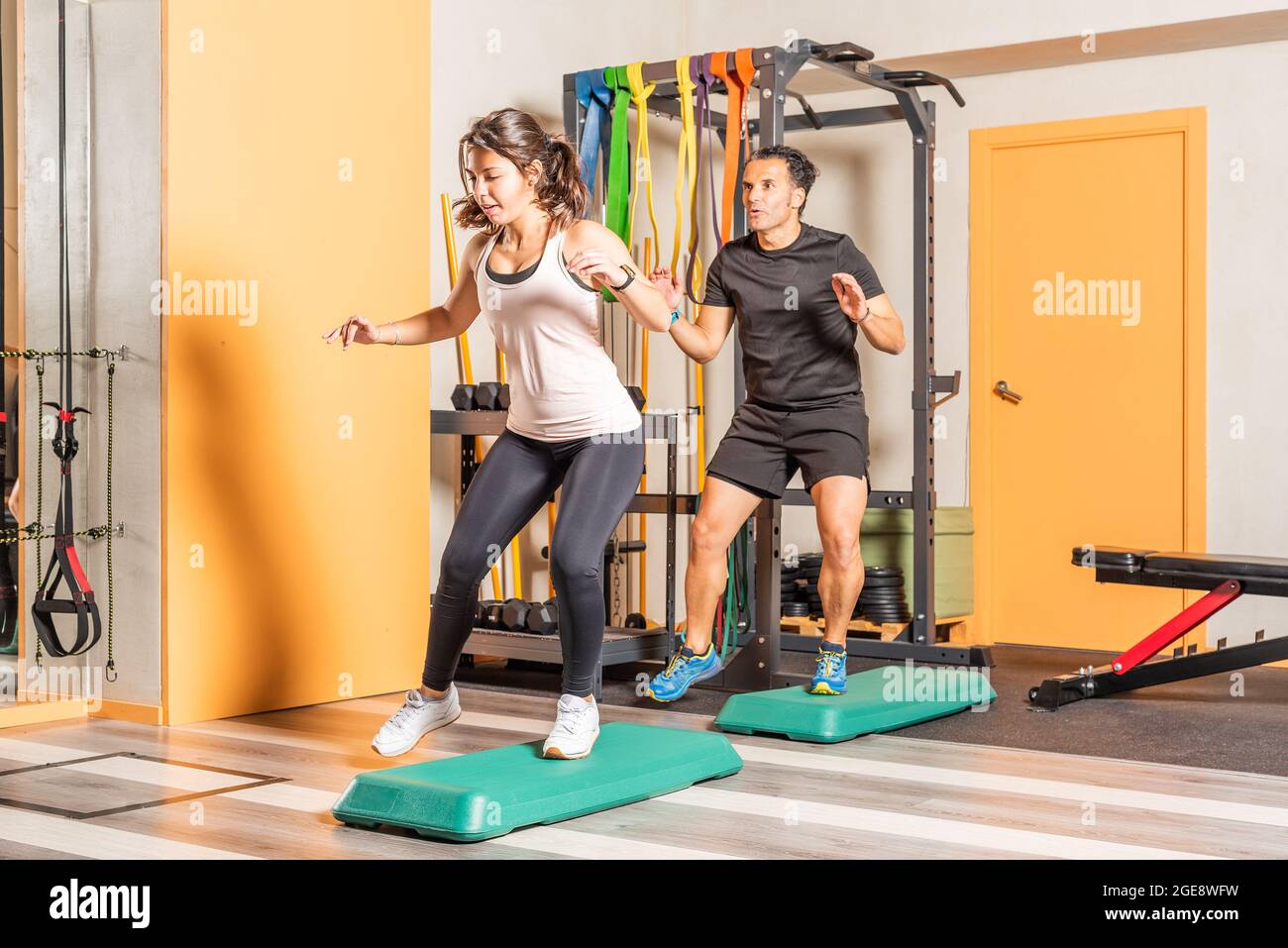 Atleta mujer y hombre haciendo saltos laterales en el club de salud Foto de stock