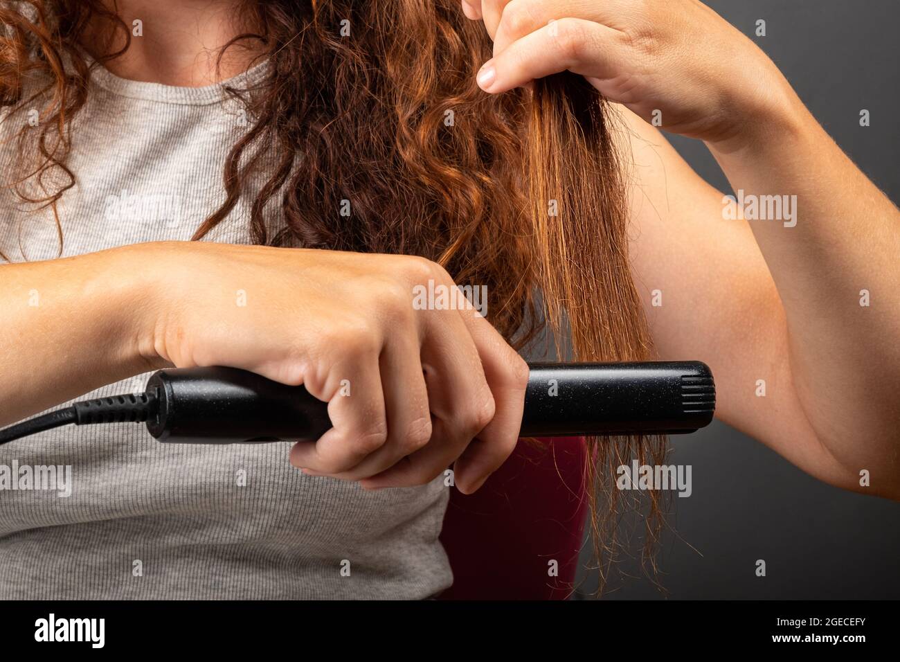 chica suaviza el cabello rizado con una plancha para el pelo, plancha para  rizar Fotografía de stock - Alamy