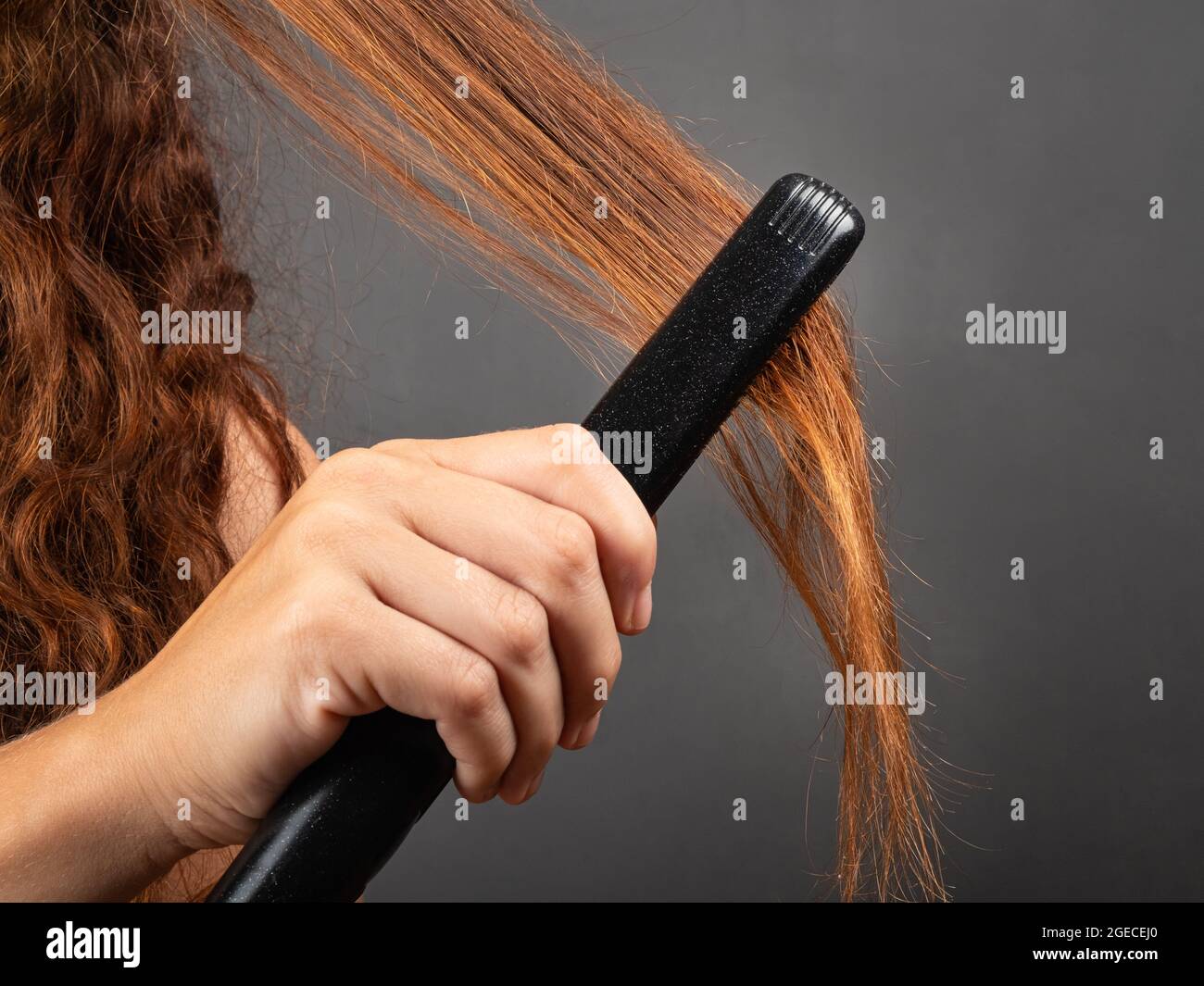 chica suaviza el cabello rizado con una plancha para el pelo, plancha para  rizar Fotografía de stock - Alamy