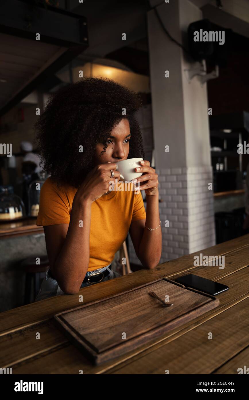 Mujer mixta bebiendo café caliente sentado en un moderno café Fotografía de  stock - Alamy