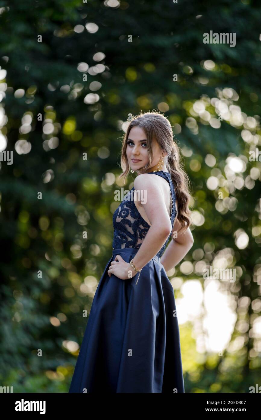 Mujer joven de pelo largo en un elegante vestido azul oscuro está posando  en el parque Fotografía de stock - Alamy