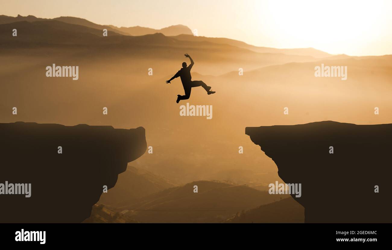Silueta saltar acantilado puesta de sol montaña. Valiente hombre Saltar entre dos acantilados. Concepto de logro de objetivos empresariales Foto de stock